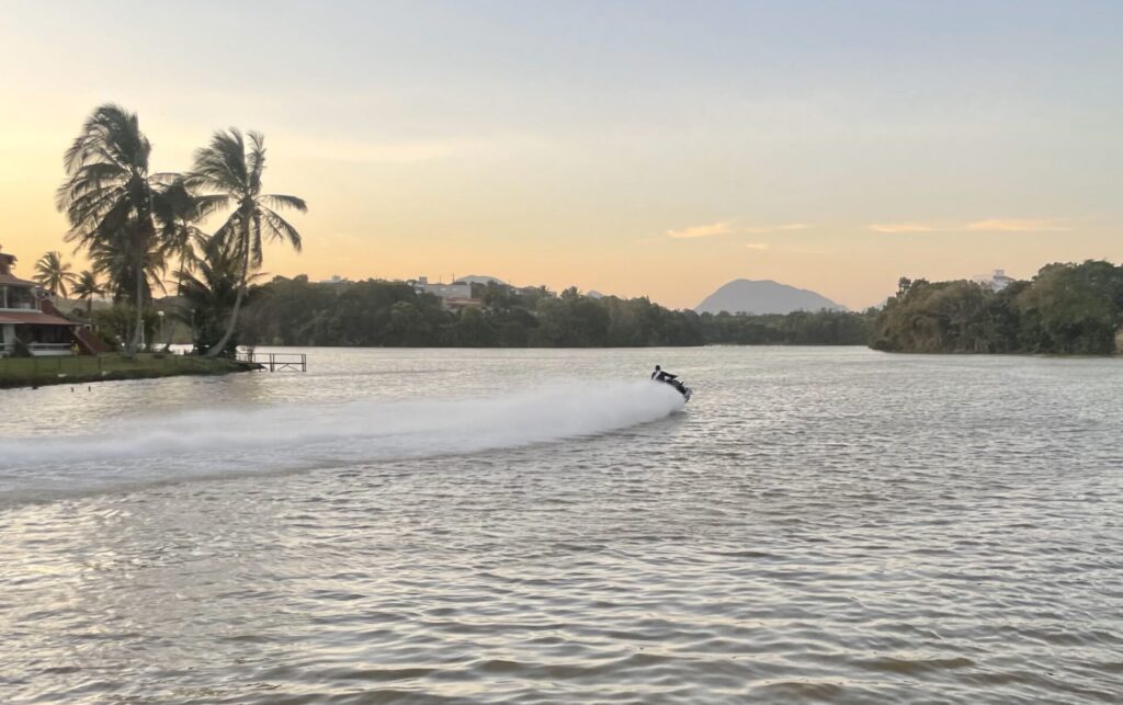 Jet ski Seadoo no horizonte em uma lagoa durante o por do sol, com vista de coqueiros, pela perspectiva da escola nautica